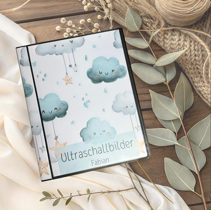 Personalisierbares Ultraschallalbum Wolken Design mit Aufschrift Ultraschallbilder und Name Fabian auf Holztisch