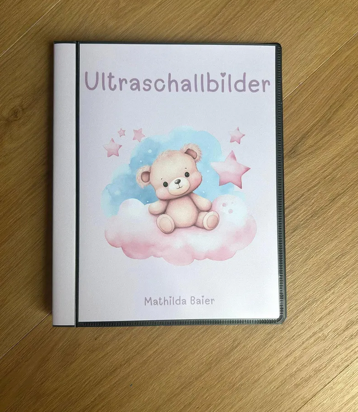 Personalisierbares Ultraschallalbum rosa Teddybär mit Aufschrift Ultraschallbilder und Name Mathilda auf Holztisch