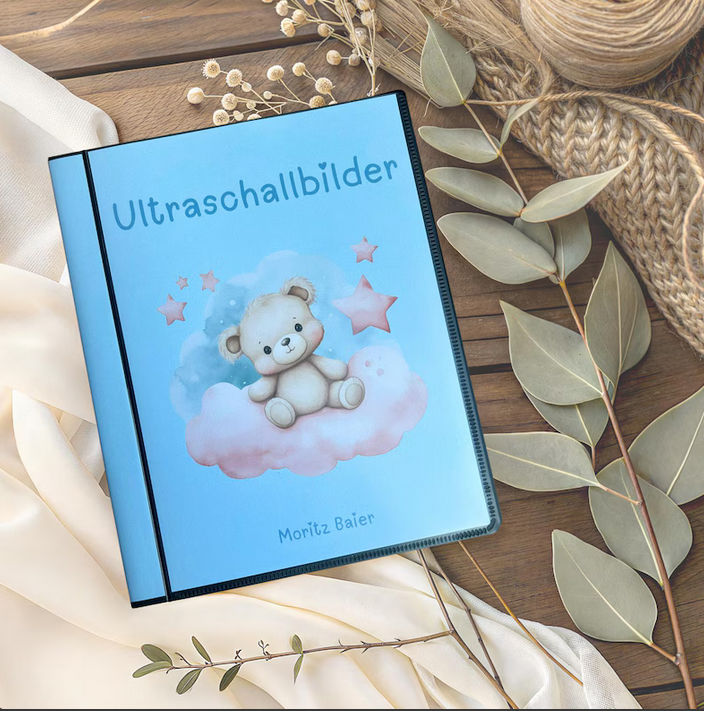 Personalisierbares Ultraschallalbum, blau, Teddybären Design mit Aufschrift Ultraschallbilder und Name Moritz auf Holztisch