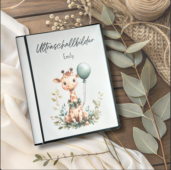 Personalisierbares Ultraschallalbum mit niedlicher Giraffe auf dem Cover mit Aufschrift Ultraschallbilder und Name Emily auf Holztisch