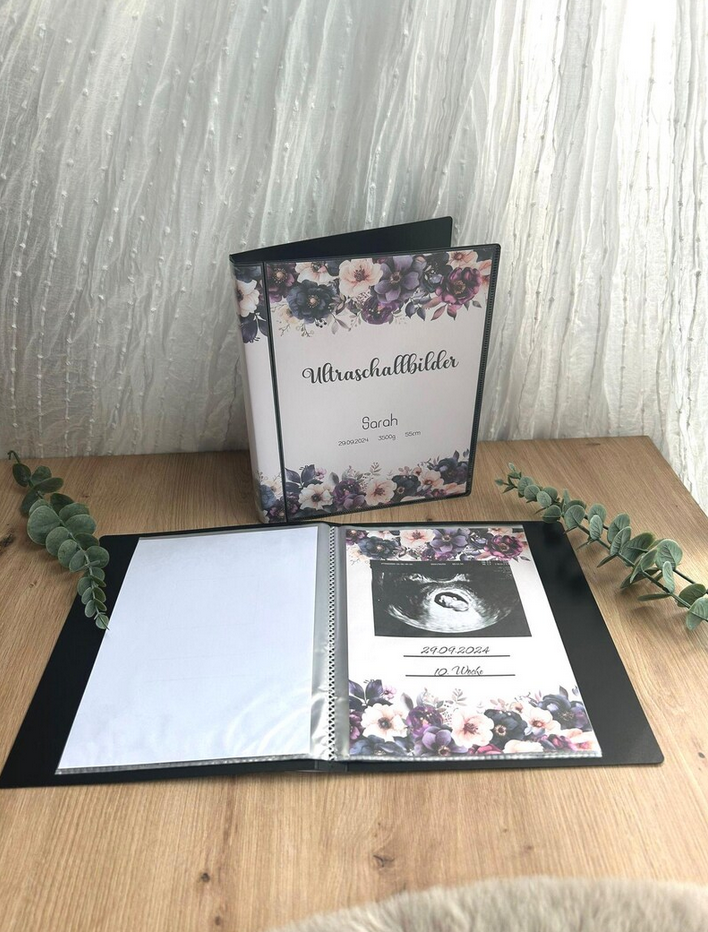 Aufgeschlagenes Ultraschallalbum mit eingeklebtem Ultraschallbild, Datum und Schwangerschaftswoche – lila Blumen