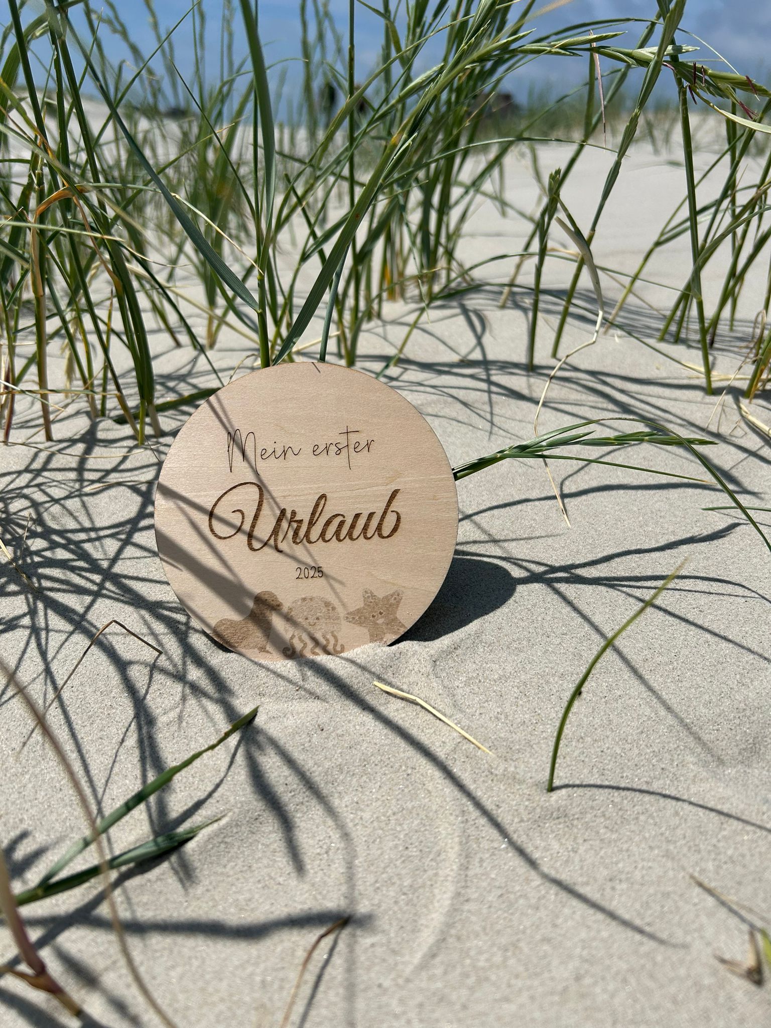 Runde Holzscheibe Mein erster Urlaub 2026 in Hand gehalten Strand Lifestyle